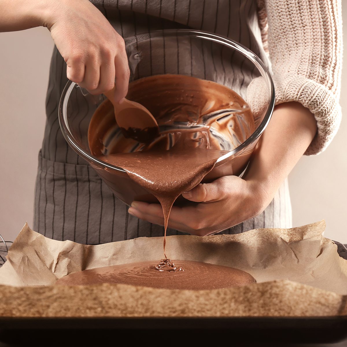 Woman pouring cacao liquid dough into baking tray