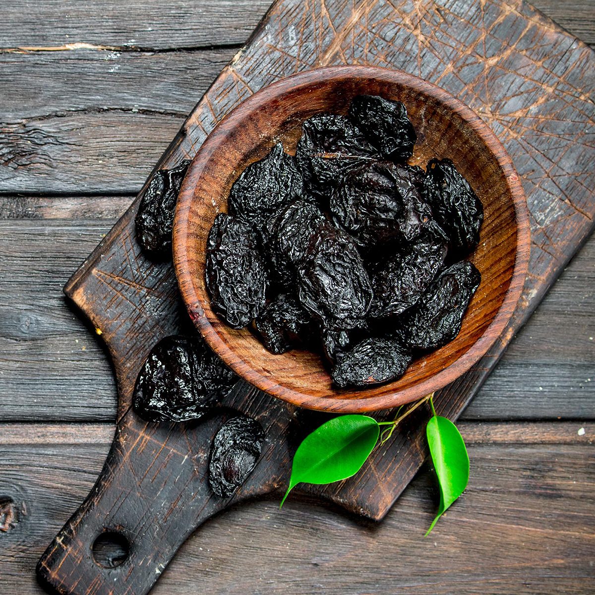 Prunes with green leaves in the bowl.
