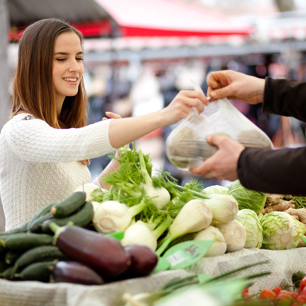 Millennial young woman buying fresh vegetables at farmer