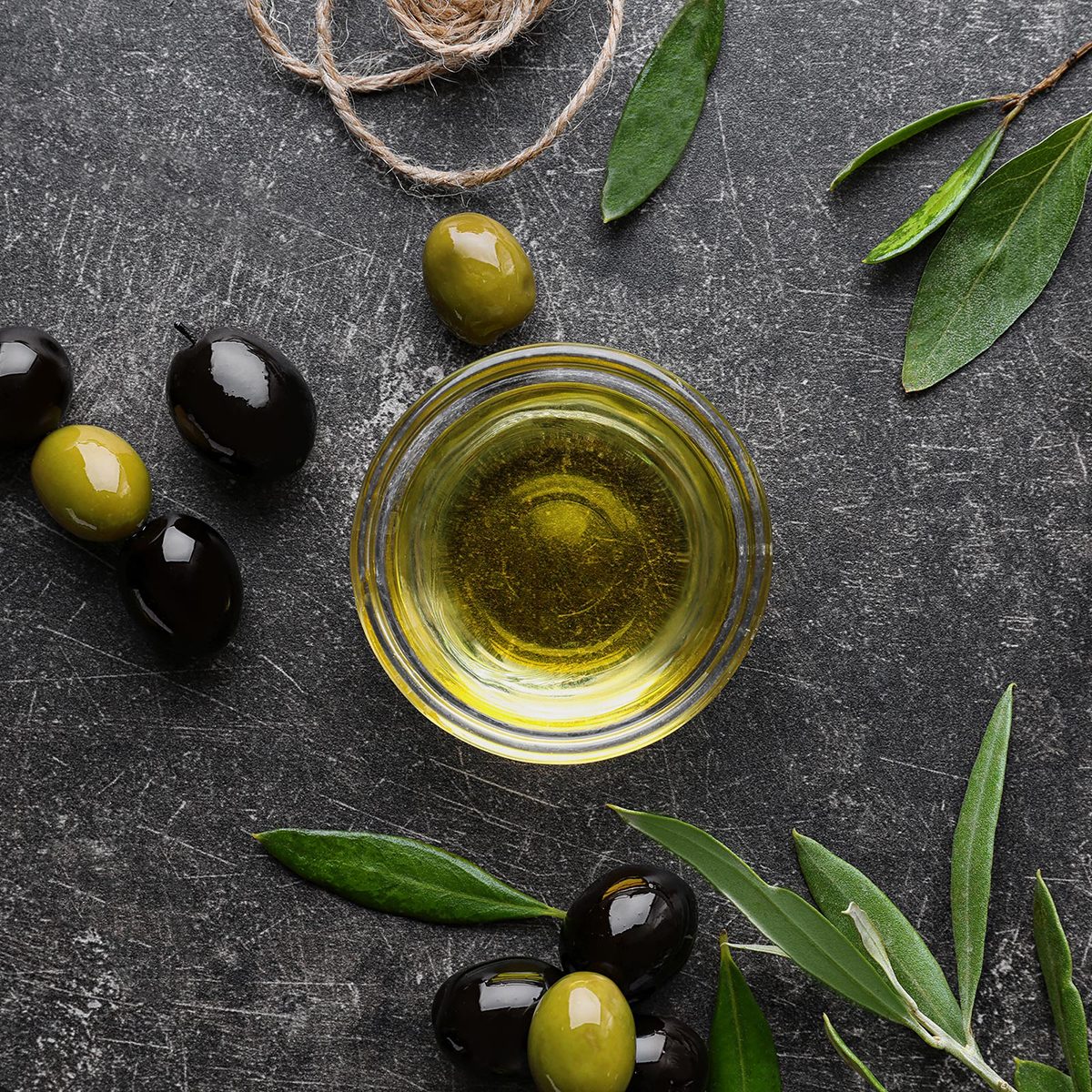 Glass bowl with olive oil on dark background