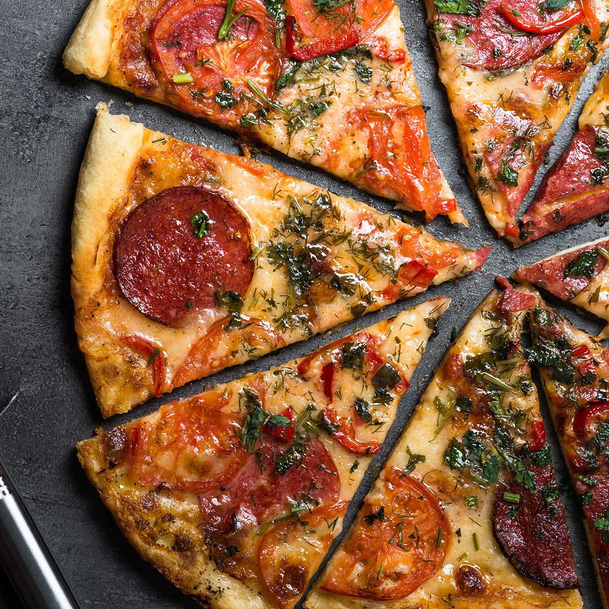 Traditional italian pizza with salami, cheese, tomatoes greens.
