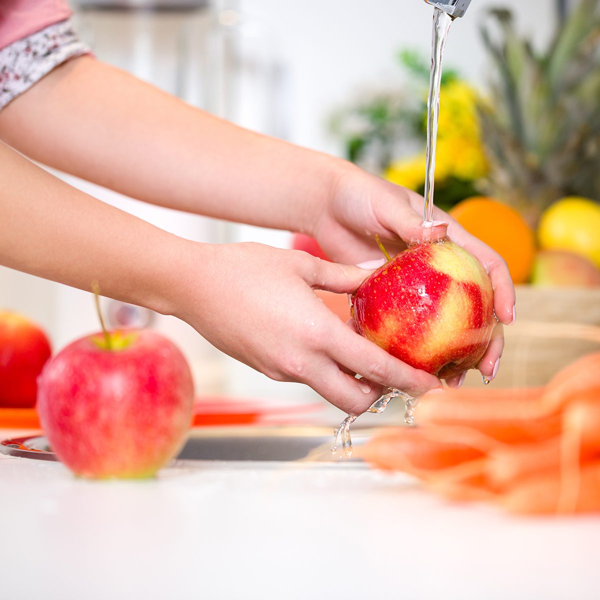 Woman hands washing tasty apple under the tap