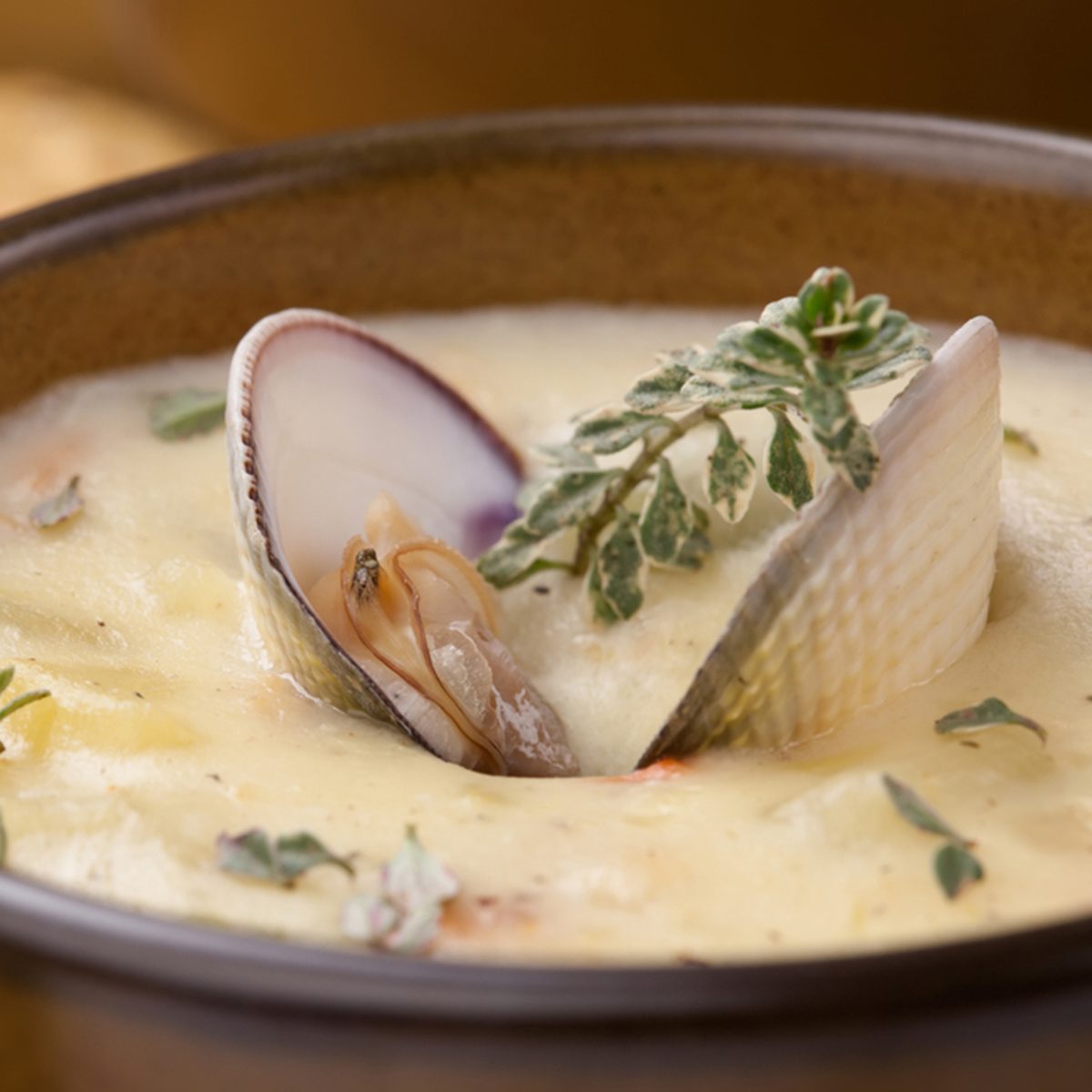 Bowls of hot delicious clam chowder garnished with fresh thyme, and multy grain crackers