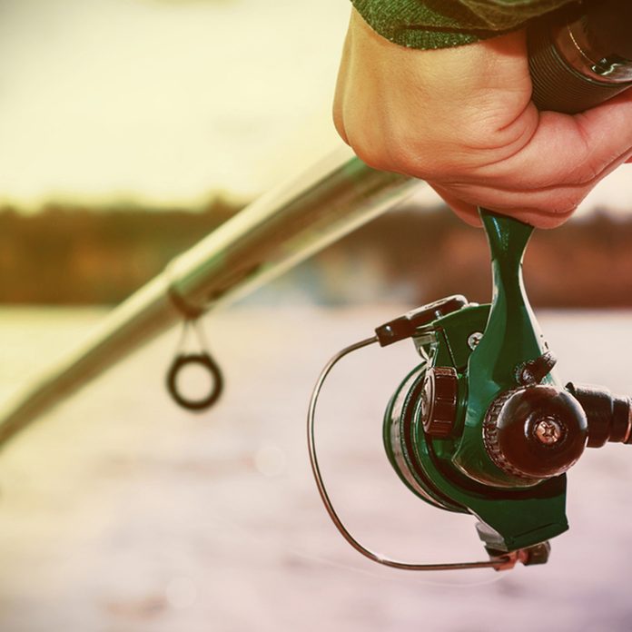 hand holding a fishing rod with reel.