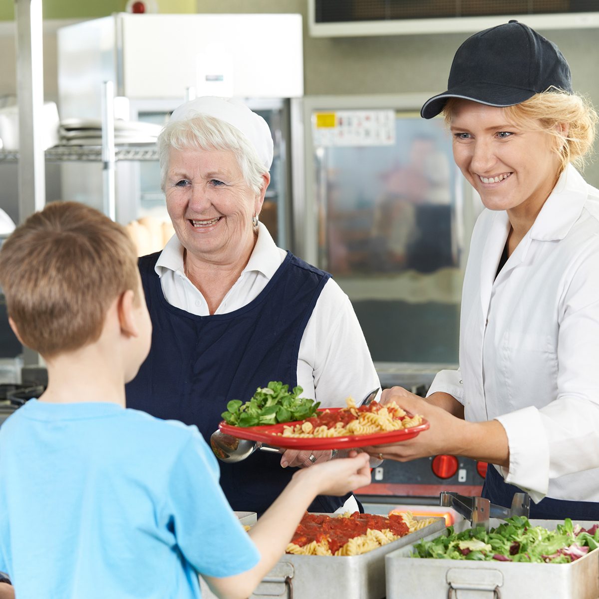 Pupils In School Cafeteria Being Served Lunch By Dinner Ladies