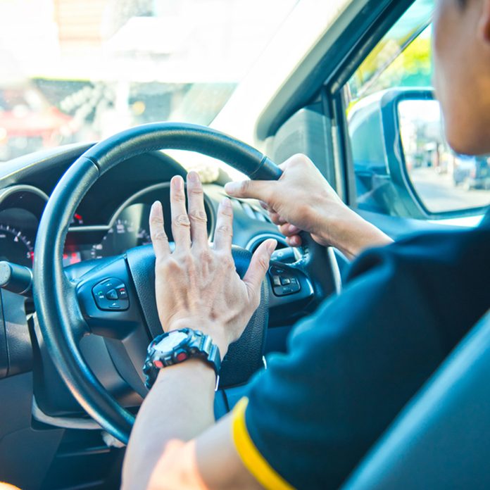 Man driving a car with hand on horn button, vintage color tone