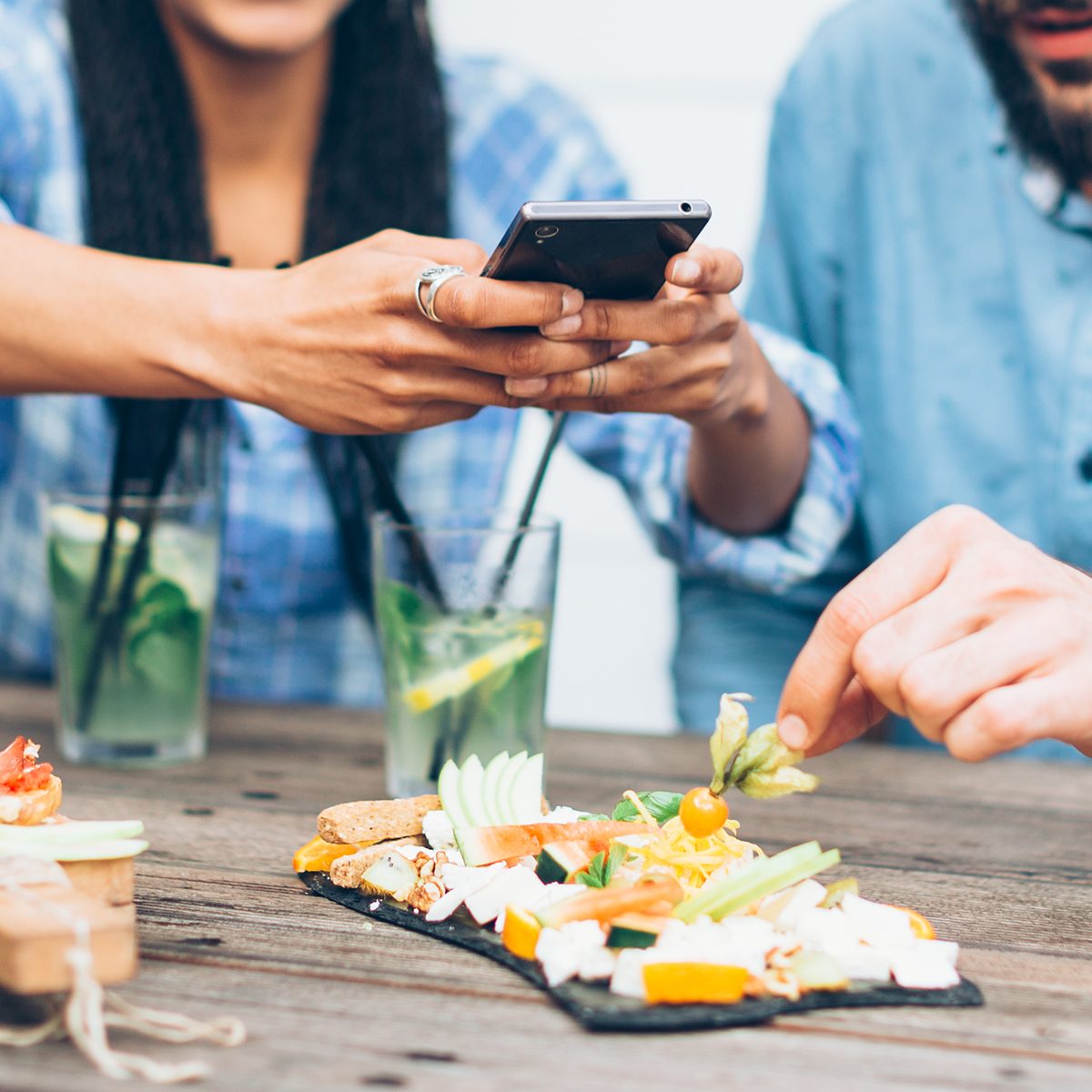 Young couple sitting in the restaurant and taking pictures of the food with mobile phone