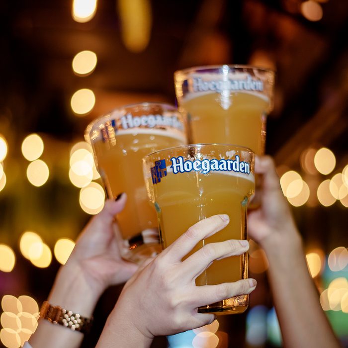 Girls Happy Holding Large Size Glass of Hoegaarden Draft Belgium Wheat Beer in Pub.