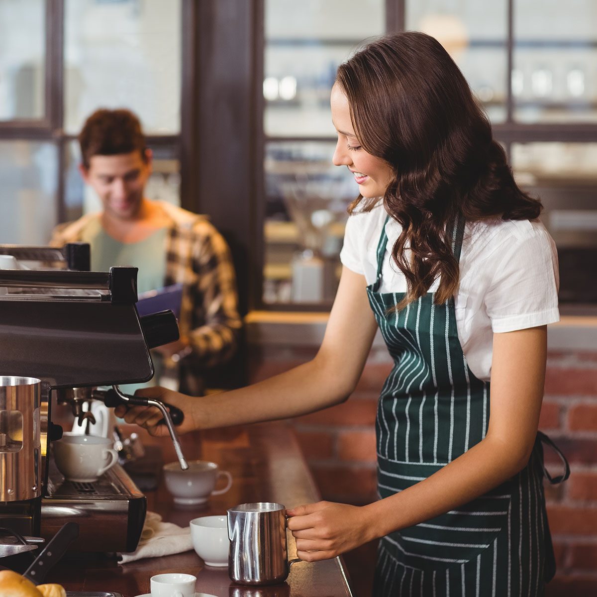 Pretty barista making a cup of coffee at the coffee shop