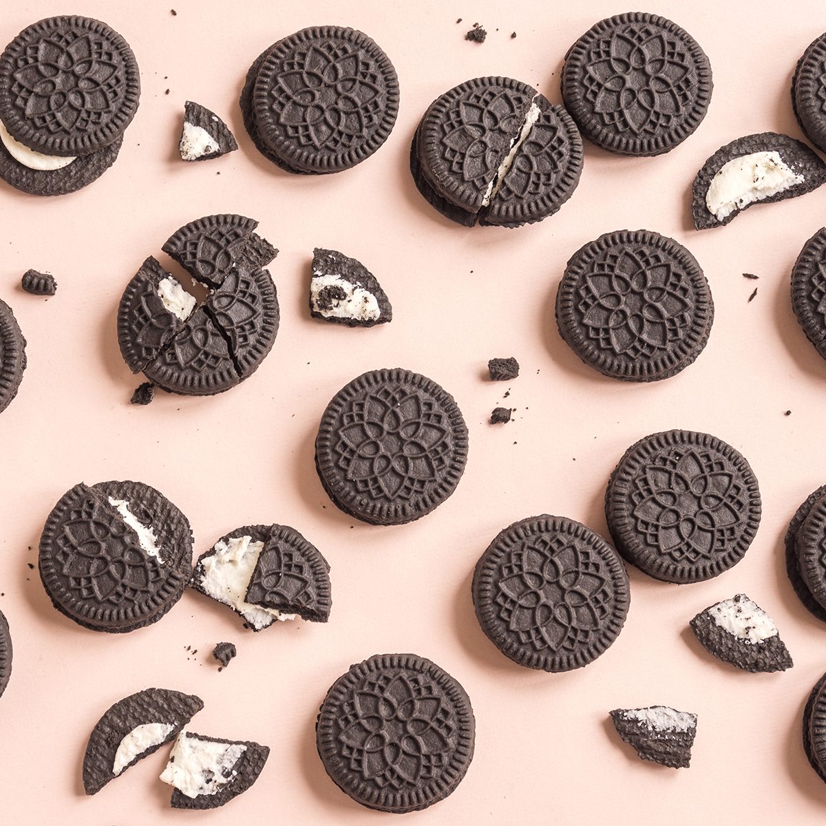 Chocolate and cream sandwich cookies on pink pastel background, top view.