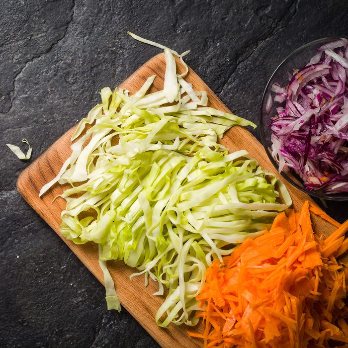Sliced carrots of cabbage and onions on a board.