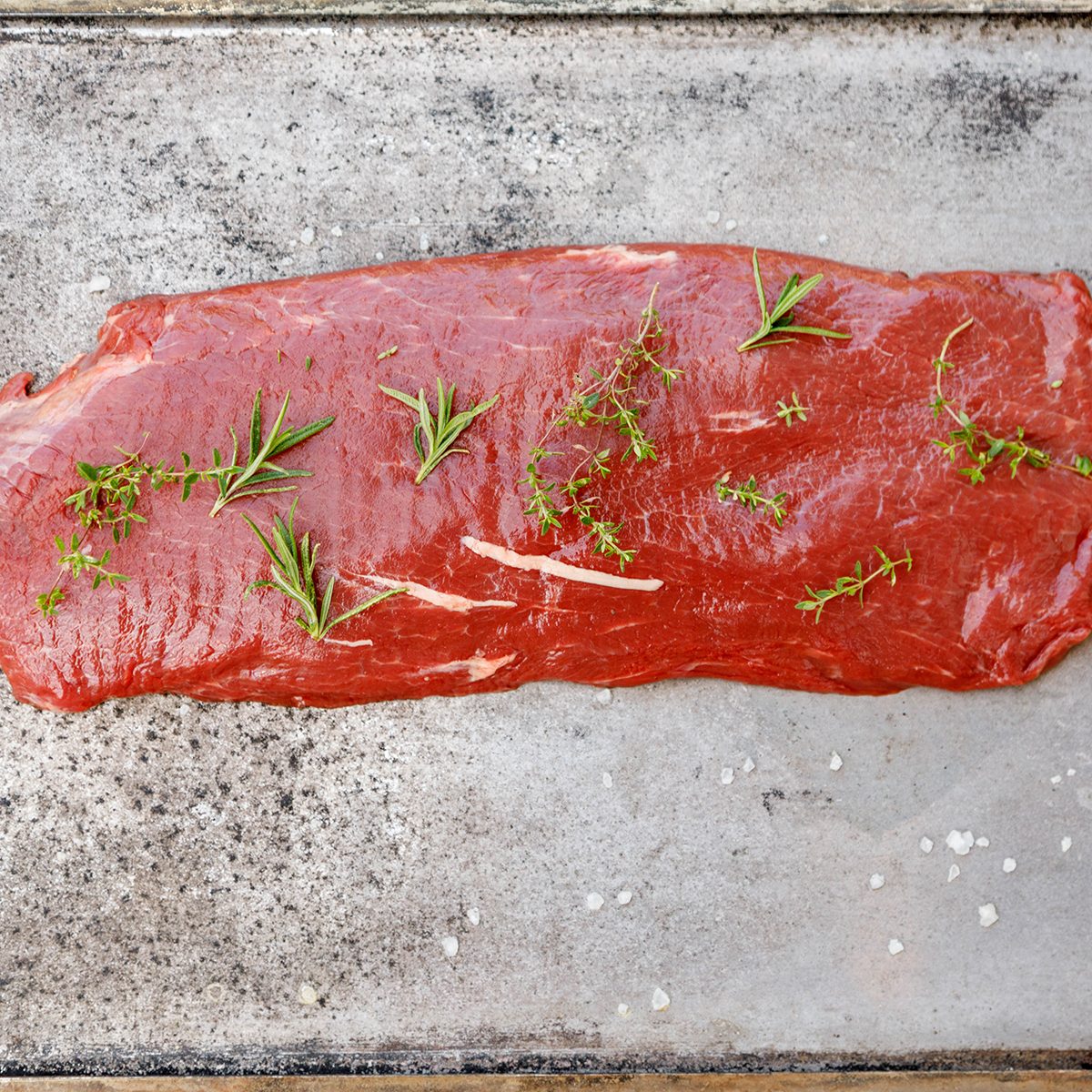 Beef Flat Iron steak on old metallic smoke tray on white background