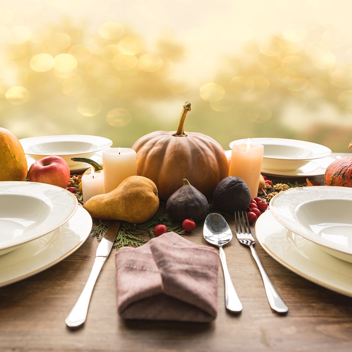Four plates with cutlery and autumnal vegetables on wooden table