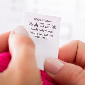 Close-up Of Person Reading The Clothing Label Showing Washing Instructions; Shutterstock ID 561901312