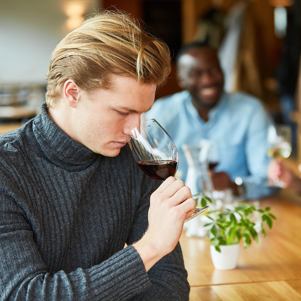 Young man at a wine tasting with a glass of red wine checks the bouquet