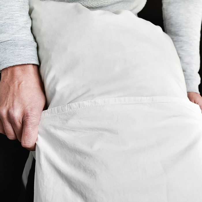 young man introducing a pillow into a pillowcase as he is making the bed