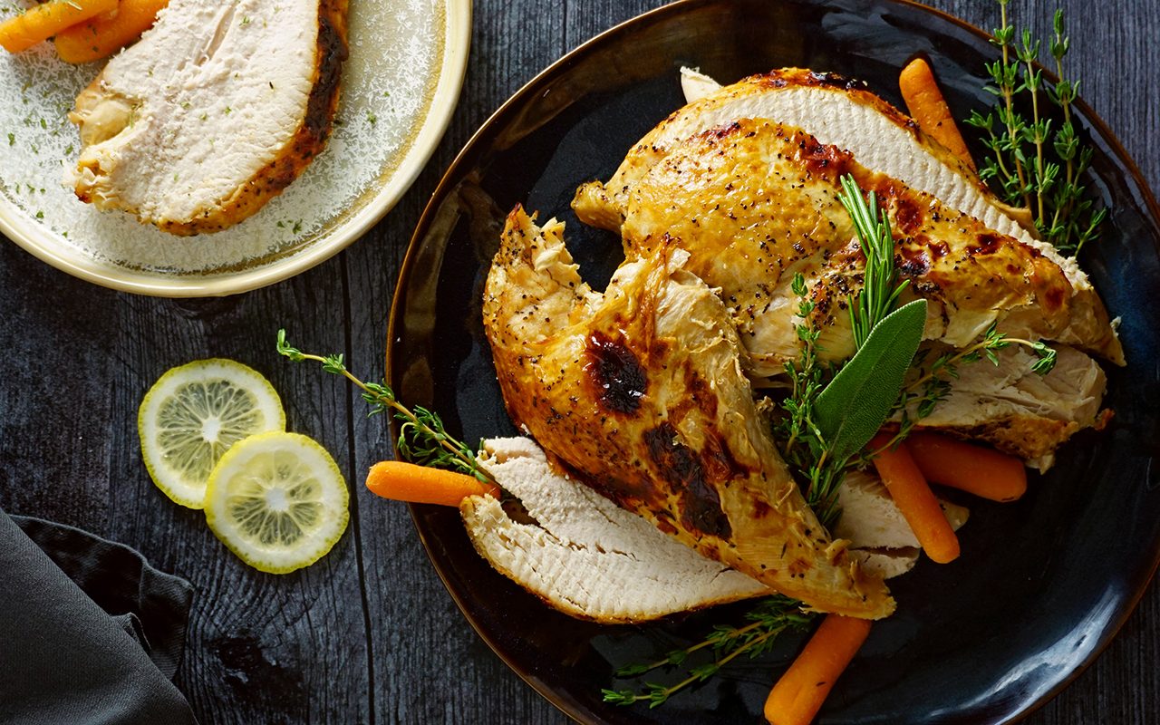 overhead shot of sliced turkey breast on a platter with a second plate of turkey in the corner