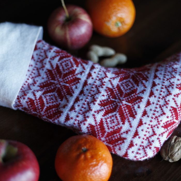 Knitted red and white Santa stocking with nuts, apples and oranges