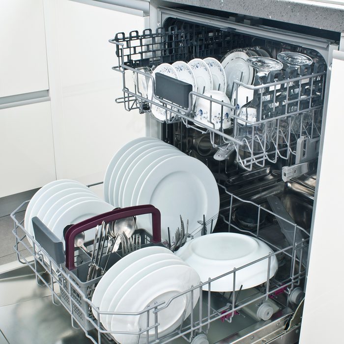 Open dishwasher with clean dishes in the white kitchen