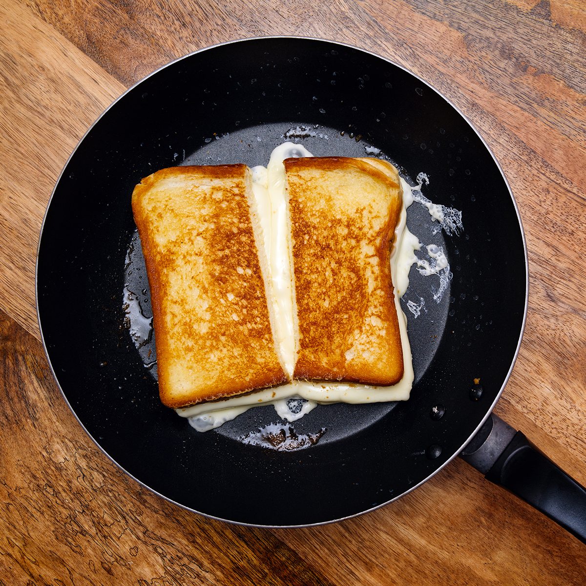 Photo of a grilled cheese sandwich cooking in a large frying pan.
