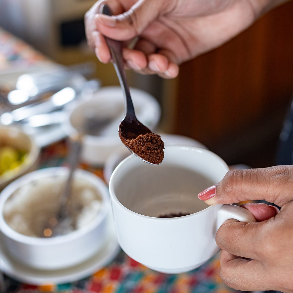 Making a coffee. Adding coffee powder. Selective focus, focus on coffee powder and spoon