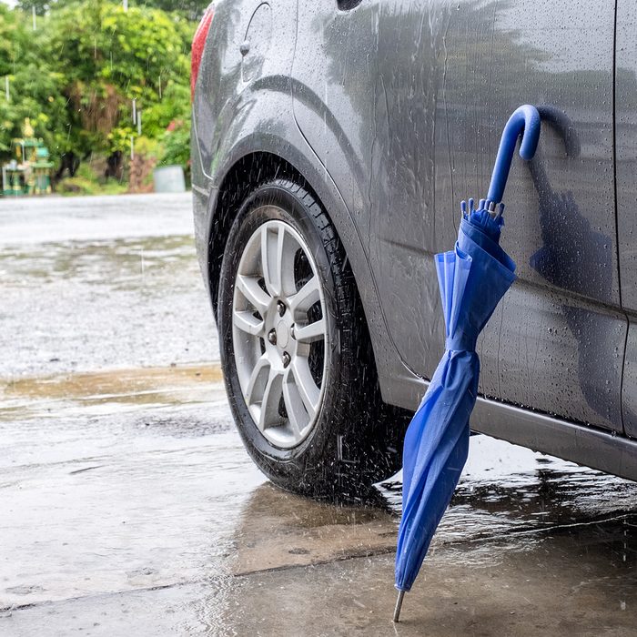 Close blue Umbrella folding with grey car in rainy