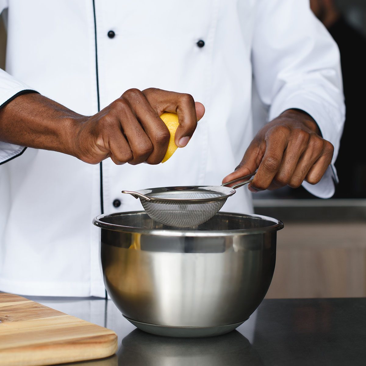 cropped image of african american chef squeezing lemons at restaurant kitchen