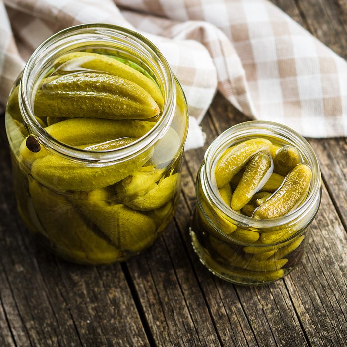 Pickles. Preserved cucumbers in jar on wooden table.