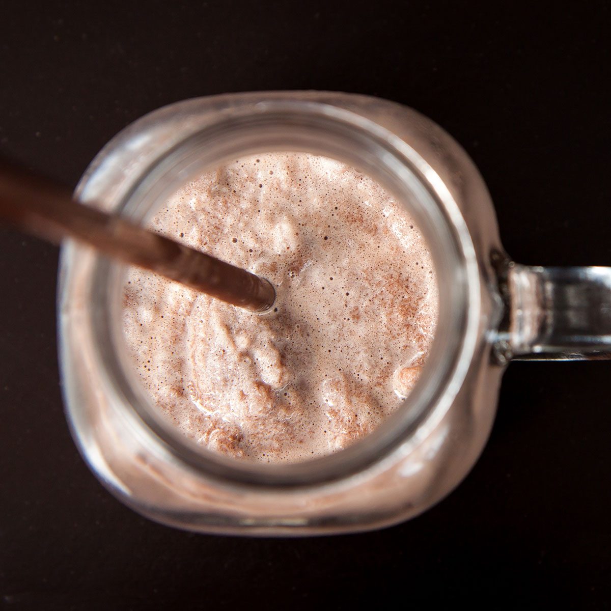 Delicious of chocolate frappe in glass cup on black wood table. Top view.