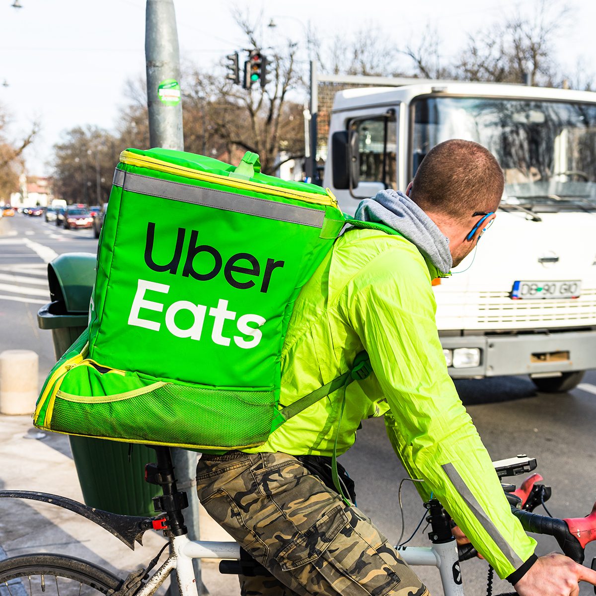 Young man on a bike with Uber Eats logo delivering food in Bucharest, Romania, 2020