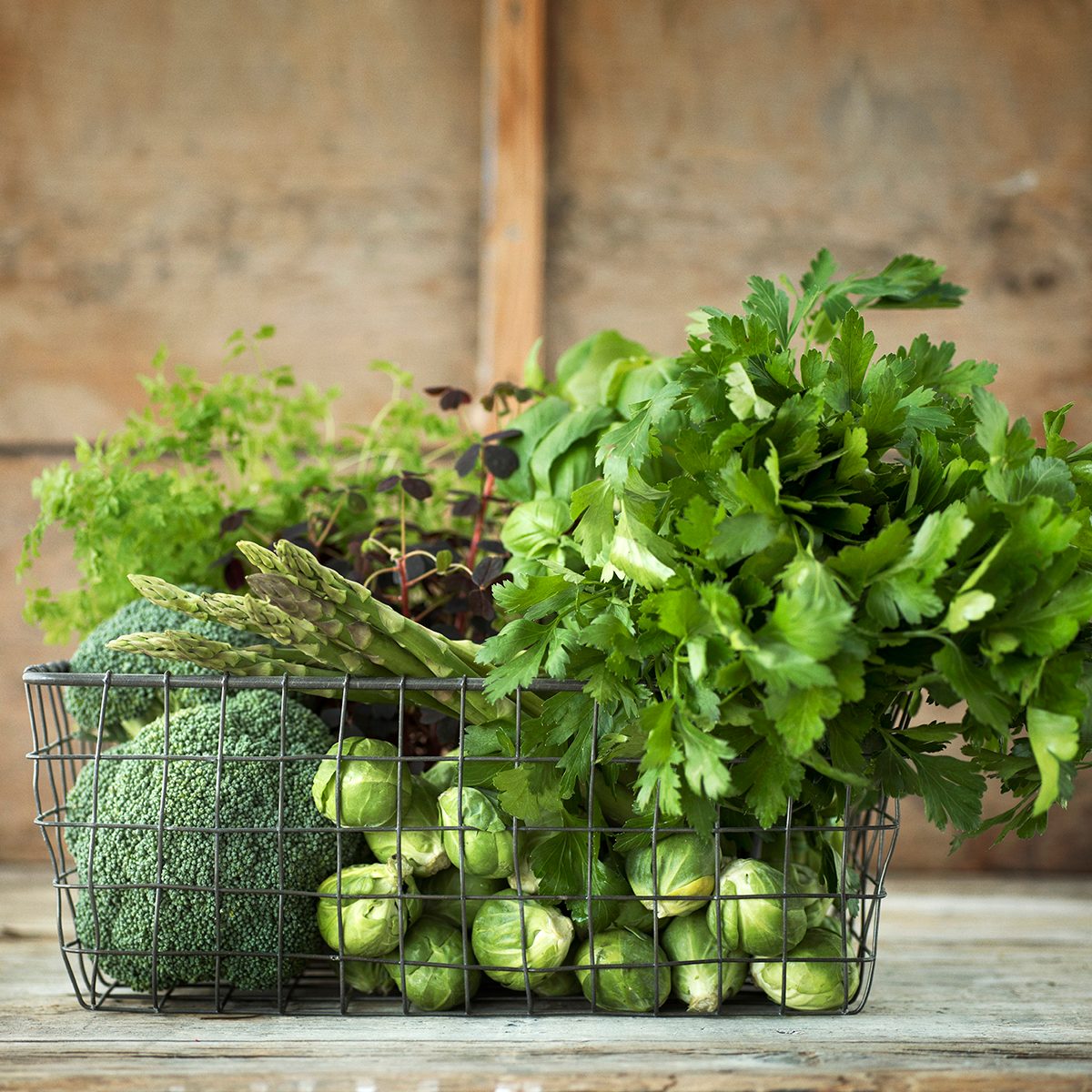 Green vegetables and herbs in wire basket