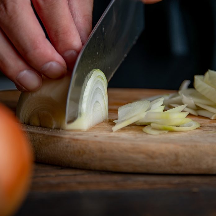 Slicing onion on cutting board in kitchen. Cooking image.