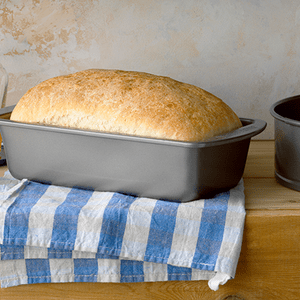 Bread in loaf pan on a towel beside a springform pan