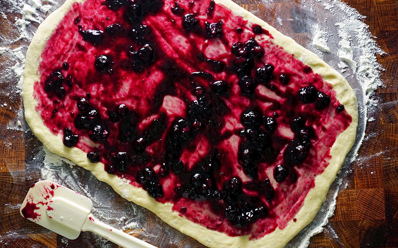 spreading filling over blueberry sweet roll dough