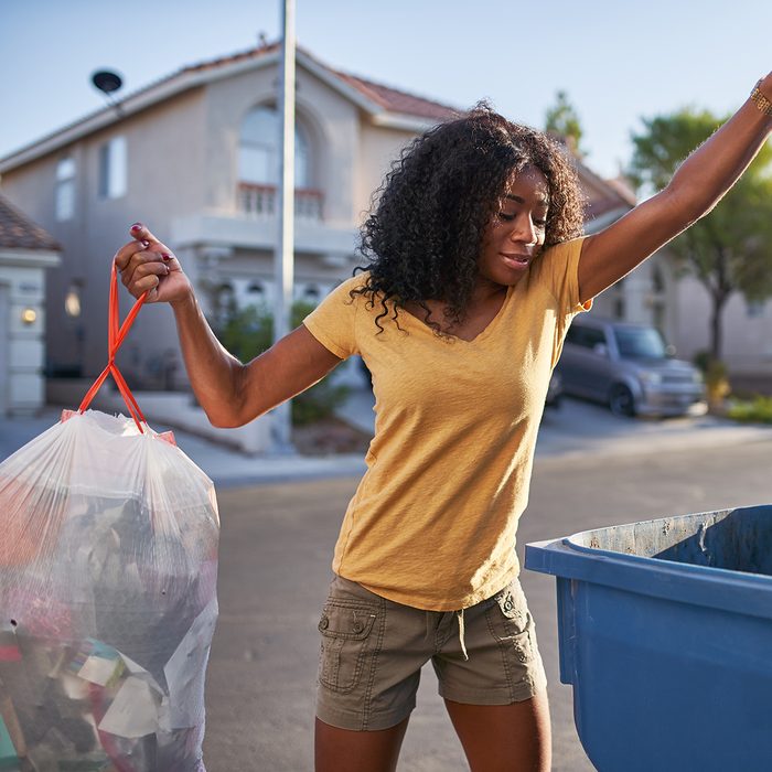 african american woman taking out the trash in las vegas neighborhood during the day