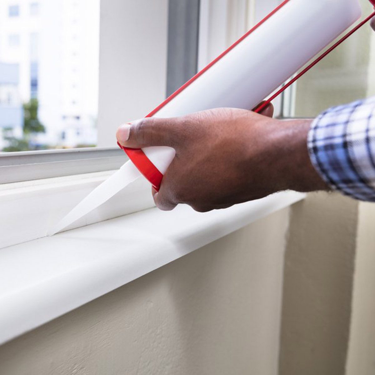 Close-up Of Person Hand Applying Silicone Sealant With Silicone Gun On Window