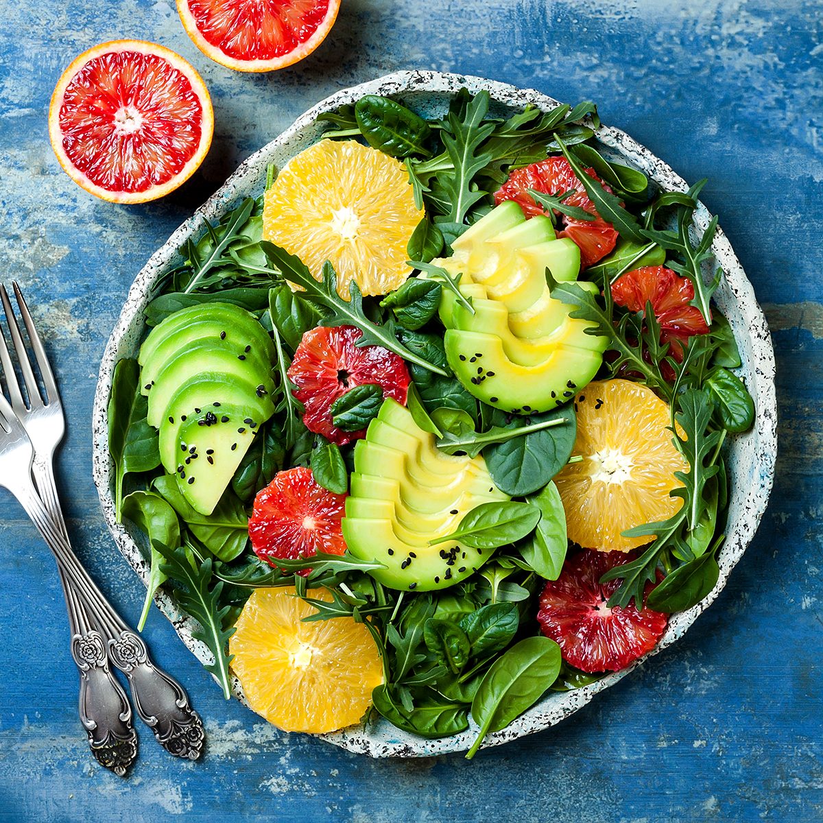 Citrus salad with mixed greens and blood orange. Vegan, vegetarian, clean eating, dieting, food concept. Blue stone background.
