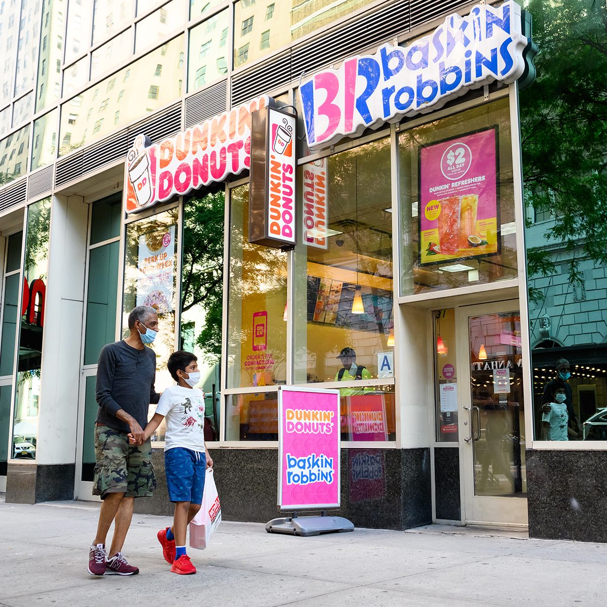 NEW YORK, NEW YORK - JULY 31: People wear protective face masks outside Dunkin