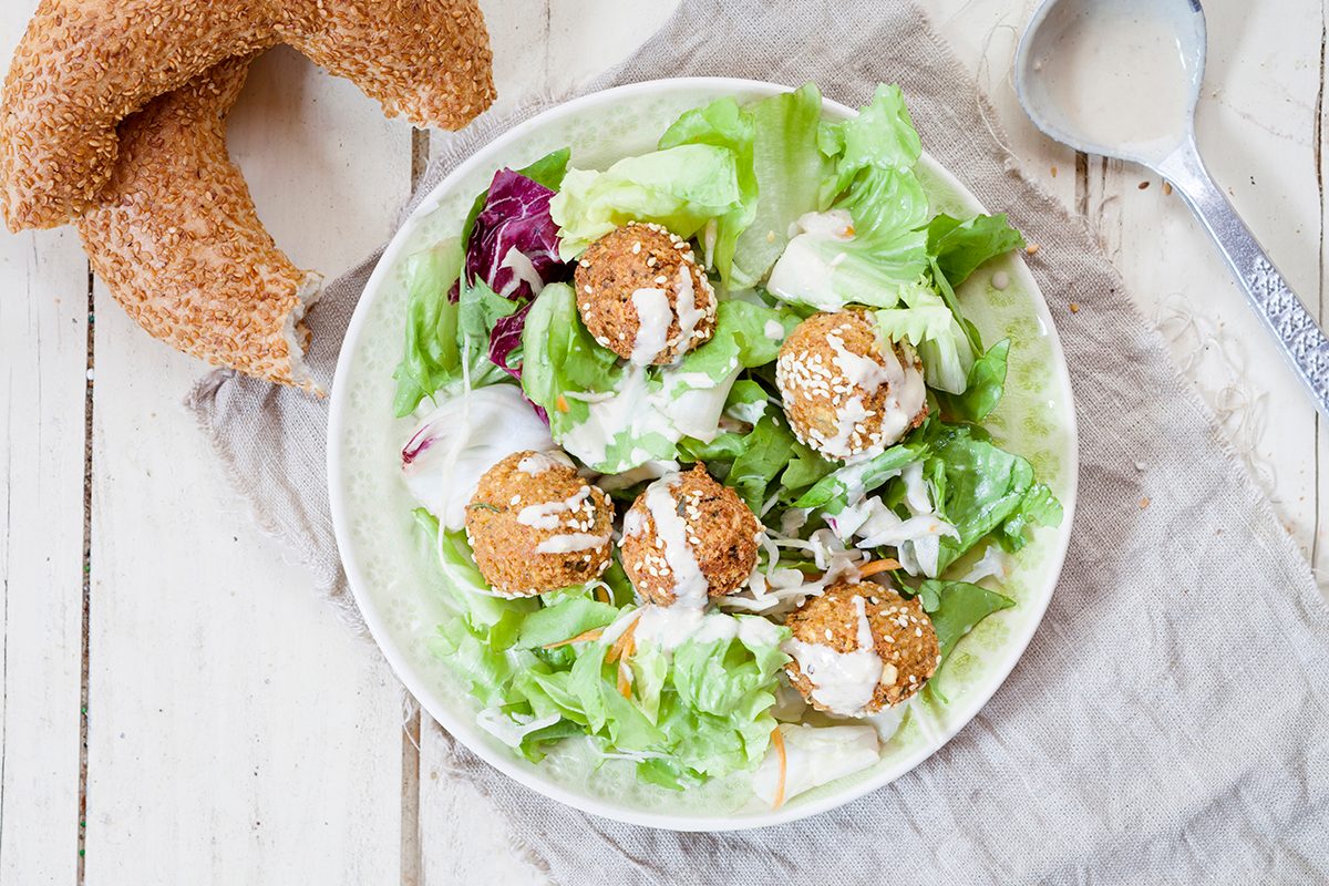 Kichererbsen-Falafel auf Salatbett mit Sesamring und Tahini-Sauce