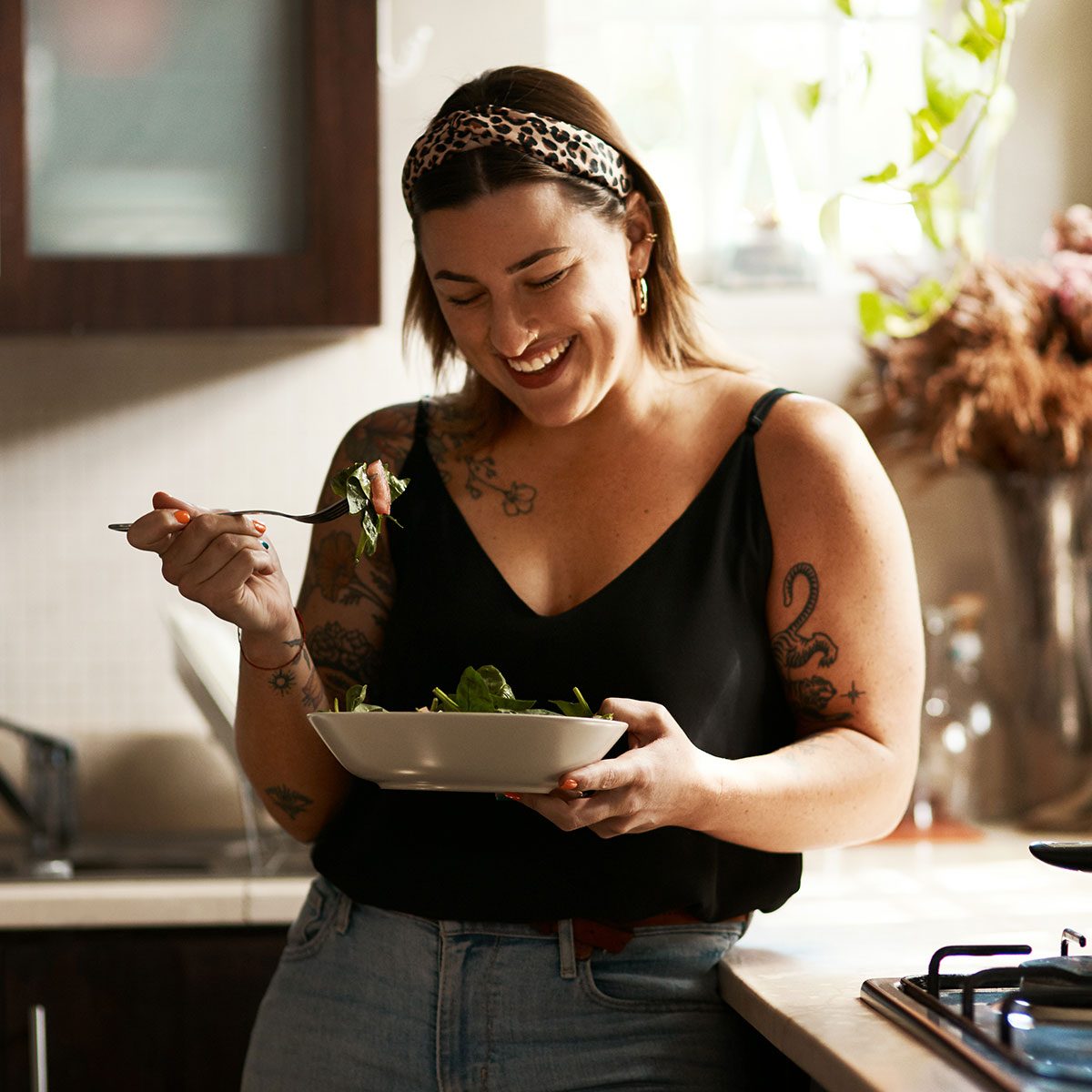 Shot of a young woman eating a healthy salad at home