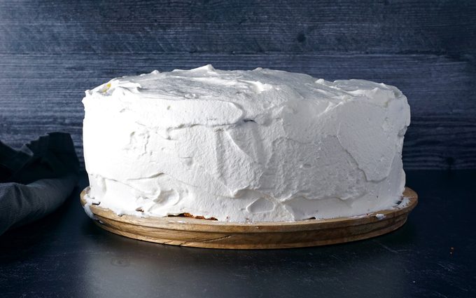 covering entire Swiss Pastry Shop Black Forest Cake with whipped cream