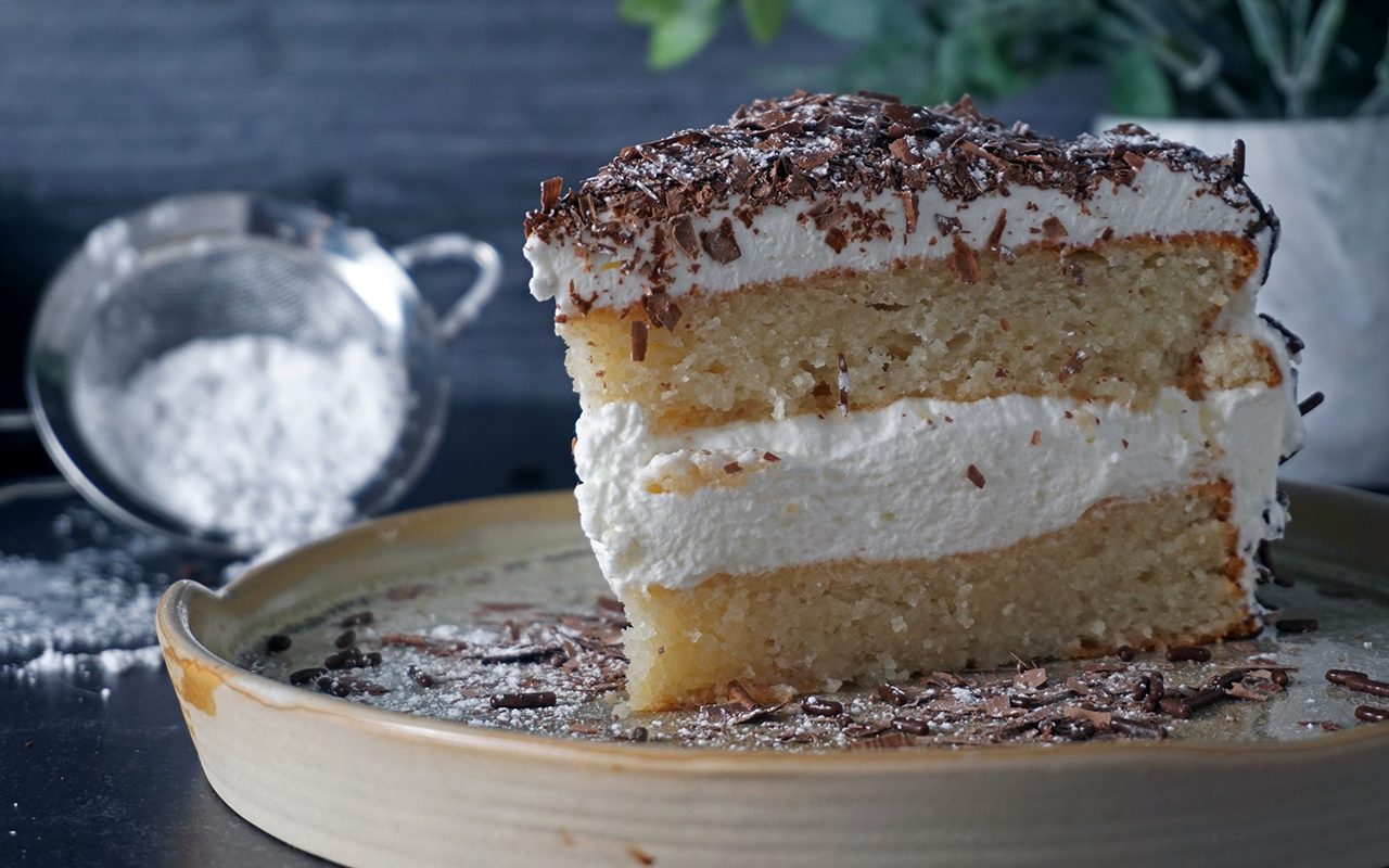 a slice of Swiss Pastry Shop Black Forest Cake on a plate garnished with chocolate shavings and powdered sugar