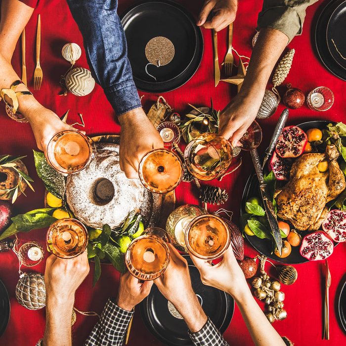 friends toasting champagne glasses at a new years dinner table with food to bring good luck