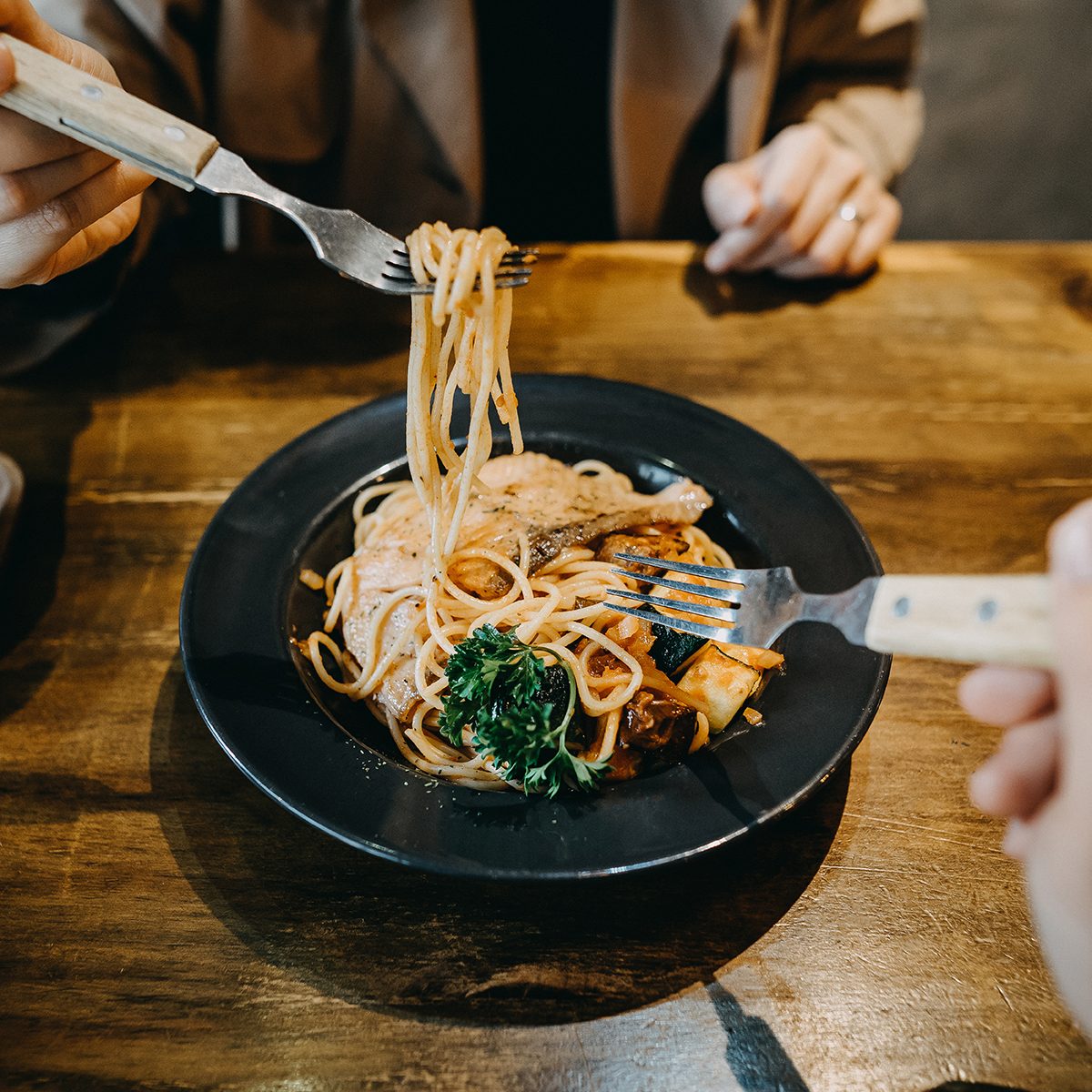 Hands Of Couple Sharing And Enjoying Freshly Made Pasta In A Restaurant