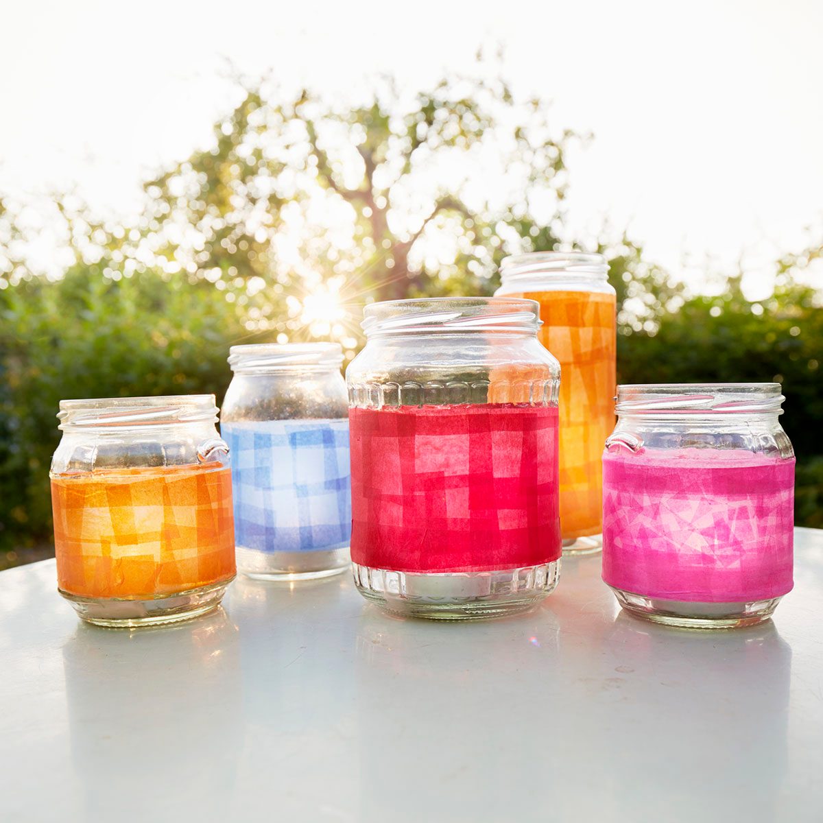 Still Life Of Handmade Lanterns On Table In Garden At Sunset