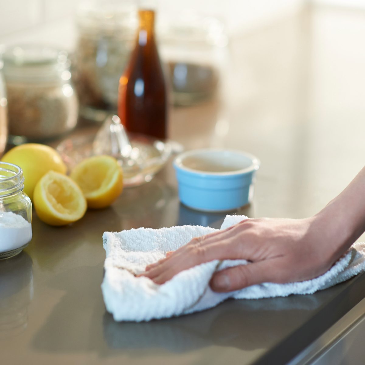 easter traditions around the world Woman cleaning a kitchen worktop with natural cleaning products lemon, bicarbonate of soda and vinegar.