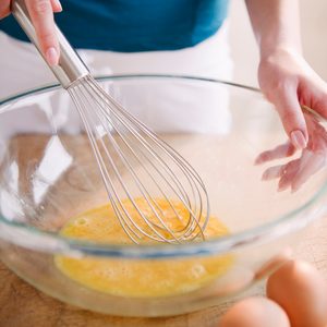 tempered eggs in bowl with wooden spoon