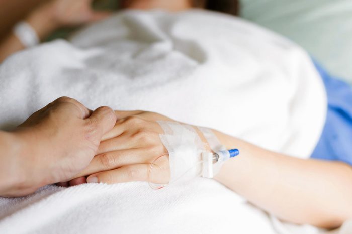 holding the hand of a person undergoing chemo treatment