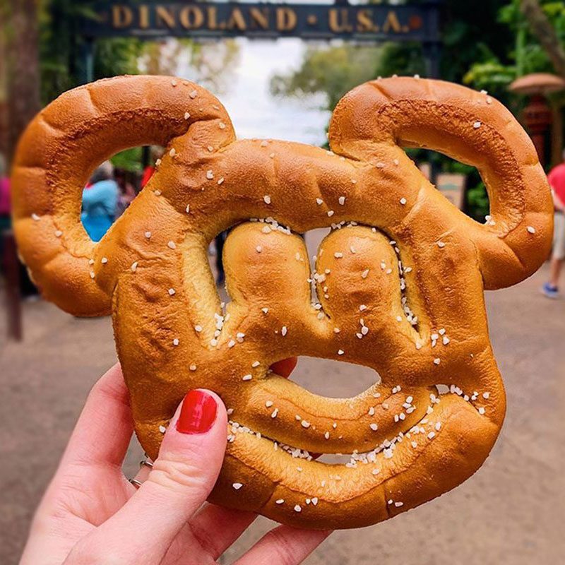 hand holding up a mickey mouse shaped pretzel at disney dinoland usa