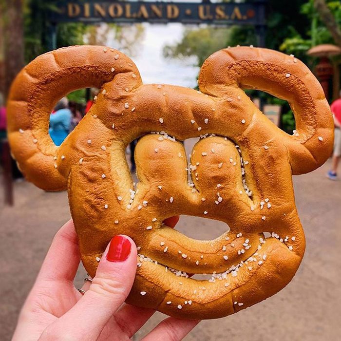 hand holding up a mickey mouse shaped pretzel at disney dinoland usa